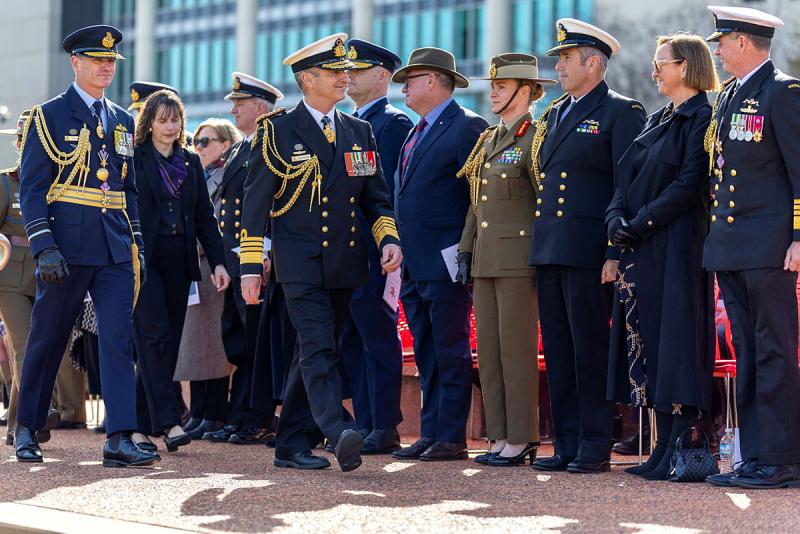 A decorated military member walks past a line-up of other military personnel.