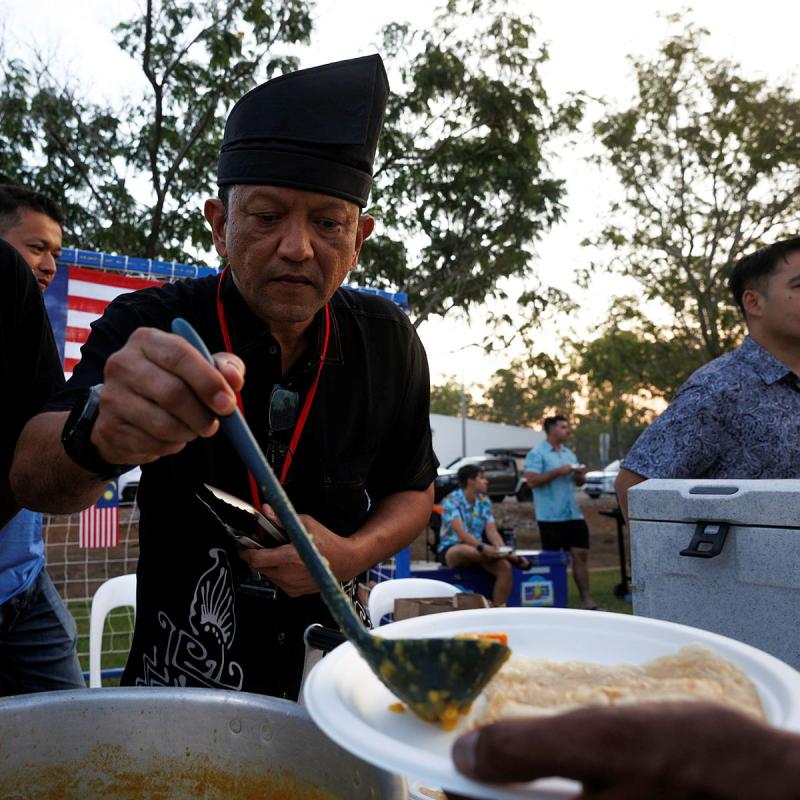 A man scoops a portion of food onto a person's plate.