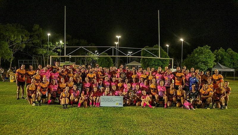 A large group of people gather on a rugby league oval with a large cheque.