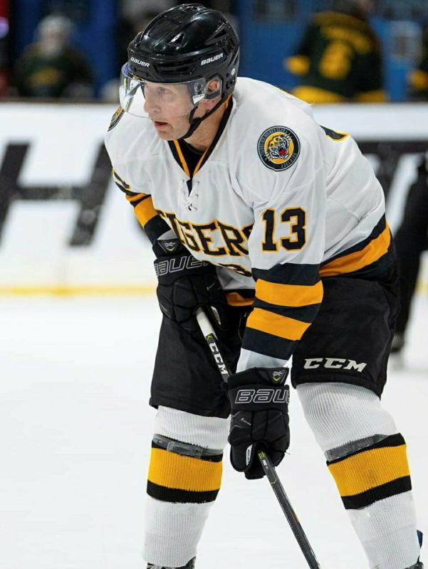 An ice hockey player aims the puck with his stick.