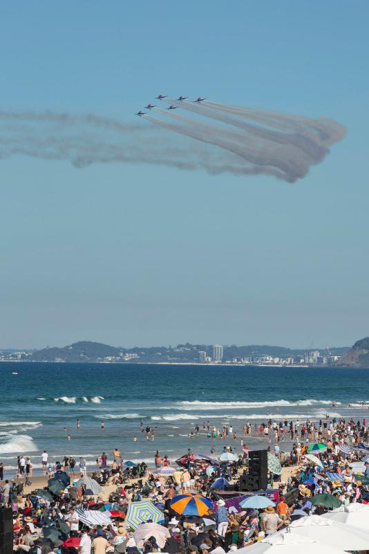 Aircraft performing an aerobatic display over crowds of people on a beach.