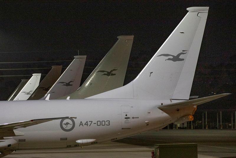 The tails of six aircraft are shown as they line up on the tarmac.