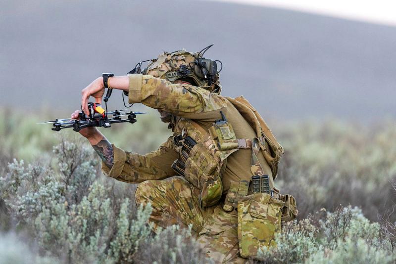 A soldier holds up a drone while he inspects it.