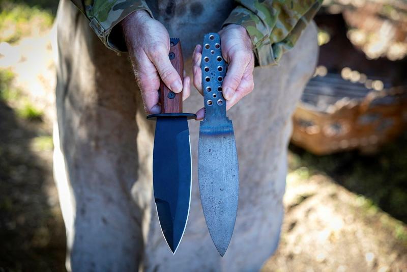 A military member holds two blades next to one another.