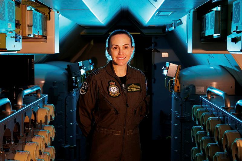 An aviator stands in the kitchen area of an aircraft.