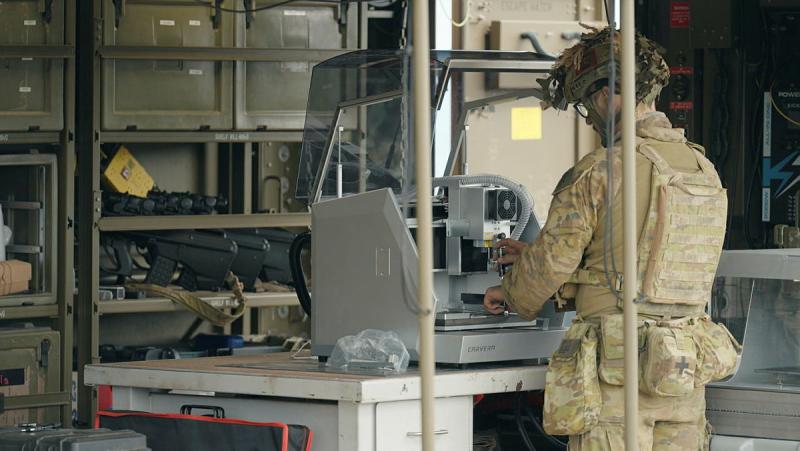 A soldier works on equipment in a fitted out Army vehicle.