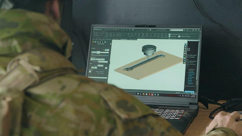 A soldier looks at a laptop screen.