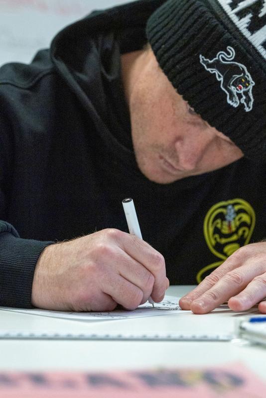 A man drawing at a table.