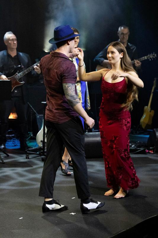 A man and woman dance in front of a band.