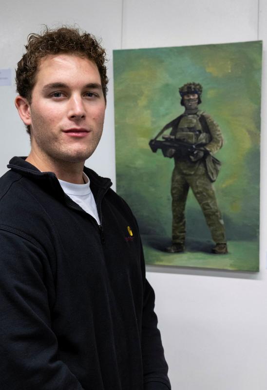 A man stands next to an oil painting of a soldier.