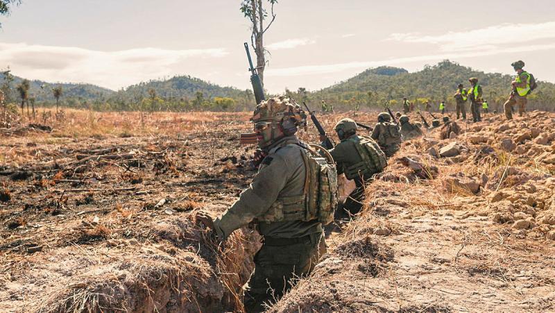Fijiian soldiers stand with guns in dug-out areas.
