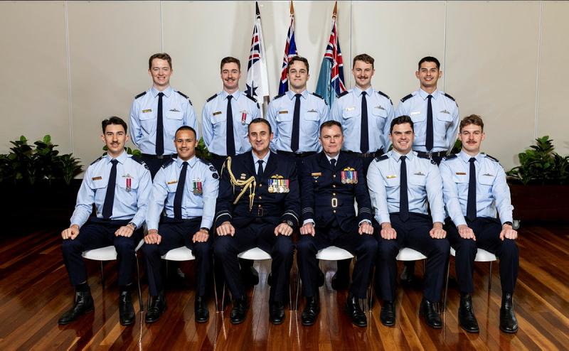 Military personnel sit and stand for a professional photo.