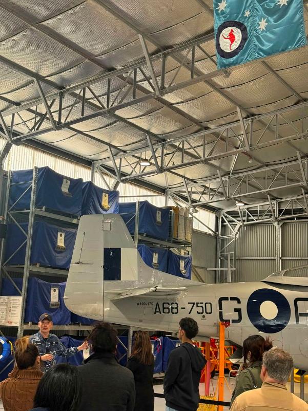 A crowd of candidates gather around the tail of an old Air Force plane.