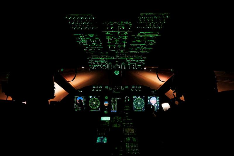 The cockpit of an aircraft in the dark, with all the buttons lit up.
