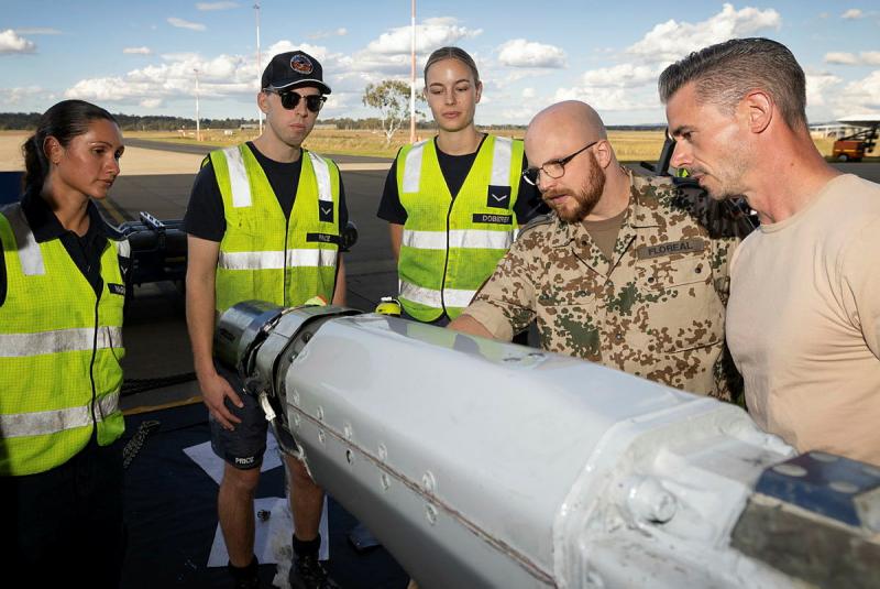 Military personnel inspect part of an aircraft.