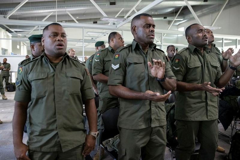 A group of Fijiian soldiers sing and clap their hands.