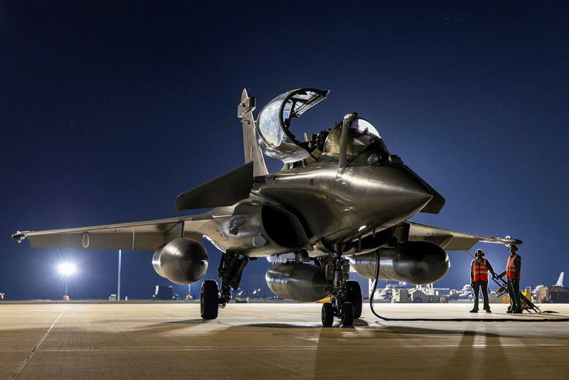 A jet aircraft with its hatch open on the tarmac a night.