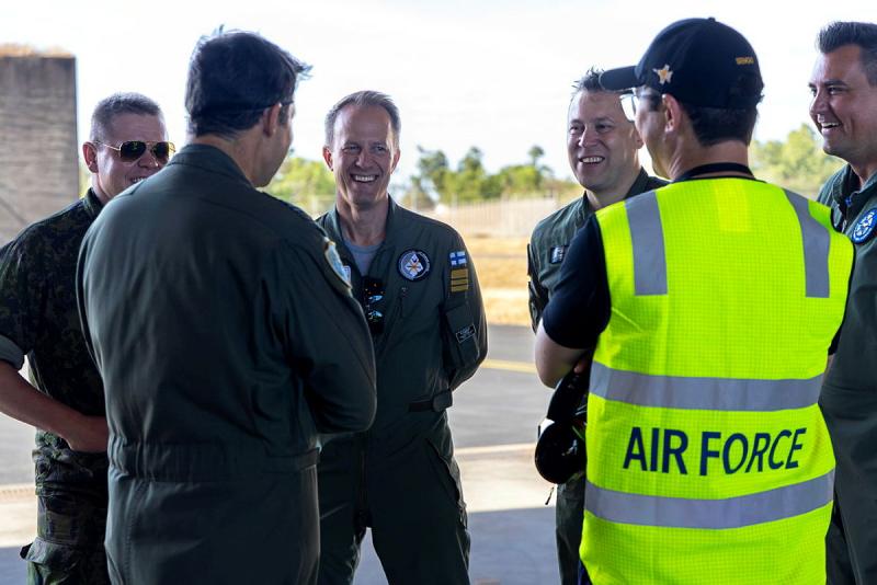 A group of aviators stand around discussing tactics and sharing stories during the exercise.