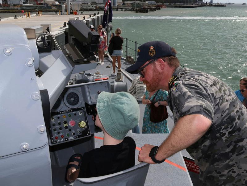 A military member shows a child part of a ship while it is docked.