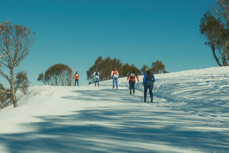 Five women ski up a slope.