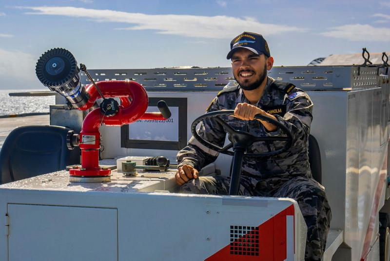A sailor in uniform drives a small vehicle.
