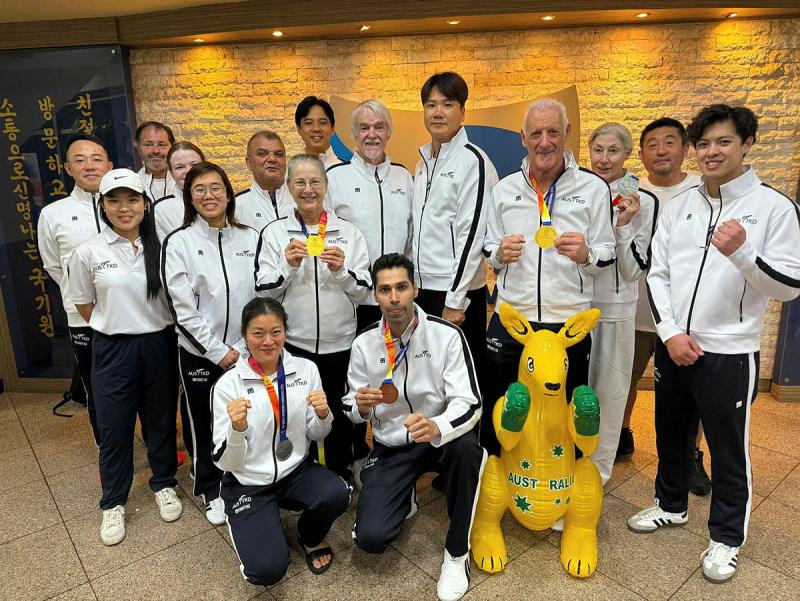 A group of men and women in matching uniform, some with medals, and a yellow Australiana kangaroo.