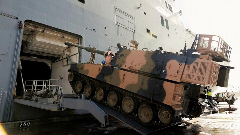 An armoured vehicle going up a ramp onto a ship.