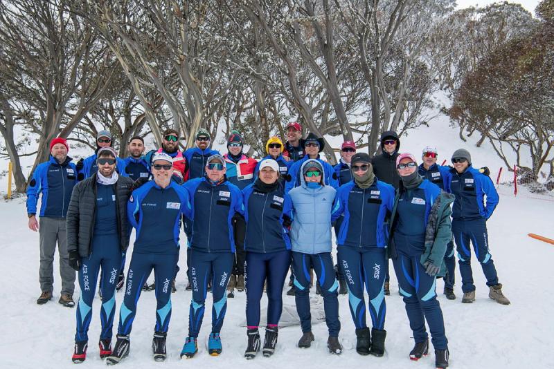 A large group of people in snow gear out in a snowy forest.