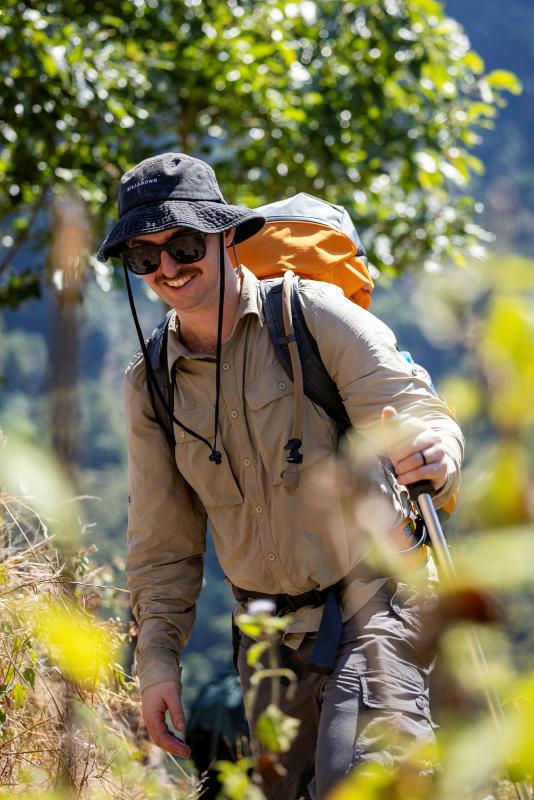 A man hikes up a steep mountain incline with a large pack.