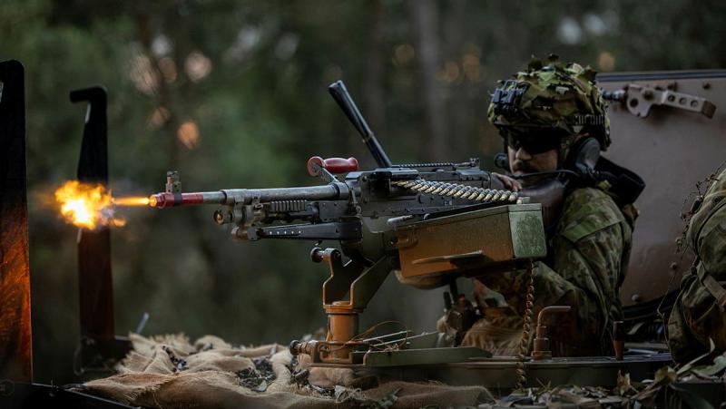An Army soldier fires a machine gun from the front of a tank during the exercise.