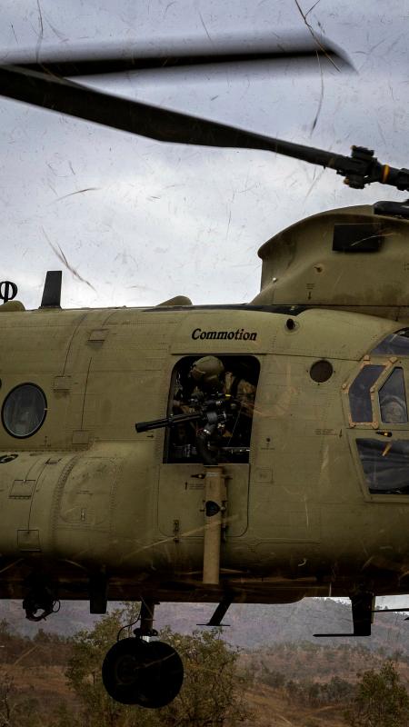 A soldier mans a gun from inside a helicopter.