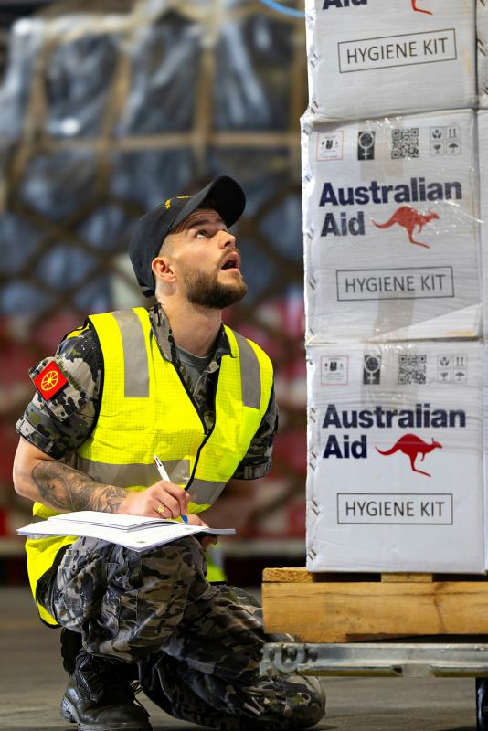A sailor inspects aid pallets.