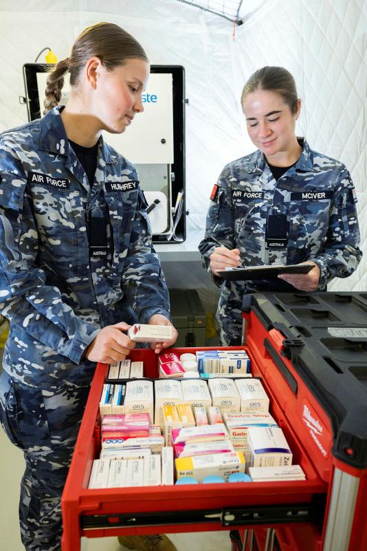 Two women in Air Force uniforms stand near a box filled with smaller labelled boxes.