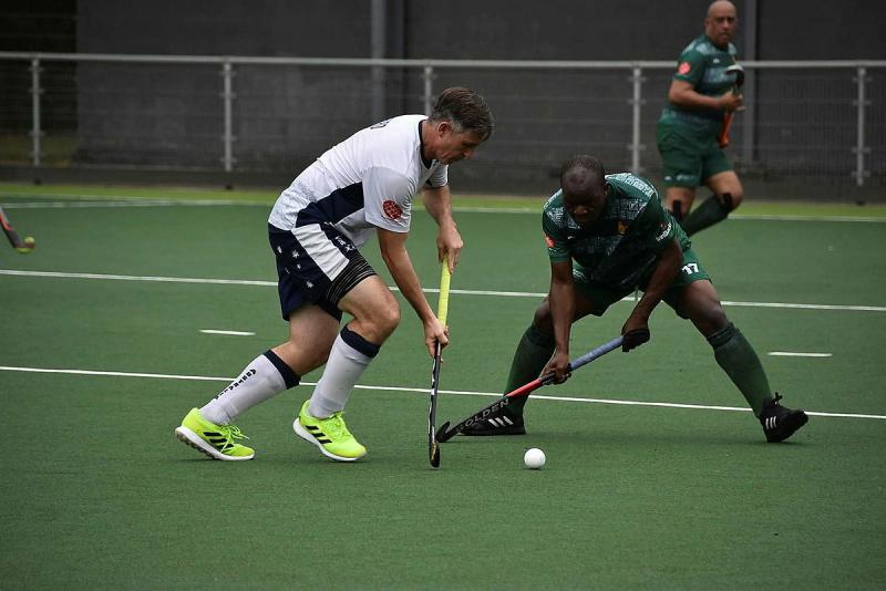 Two men battle for the hockey ball during a game of hockey.