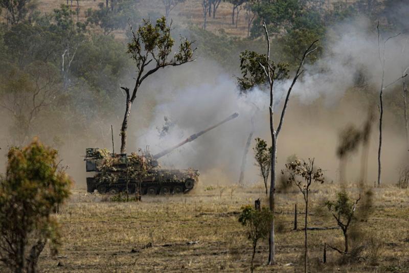 An Army tank firing in the bush.