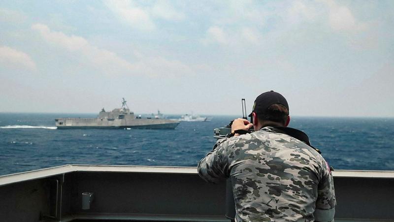 A Navy member looks through equipment at other ships.