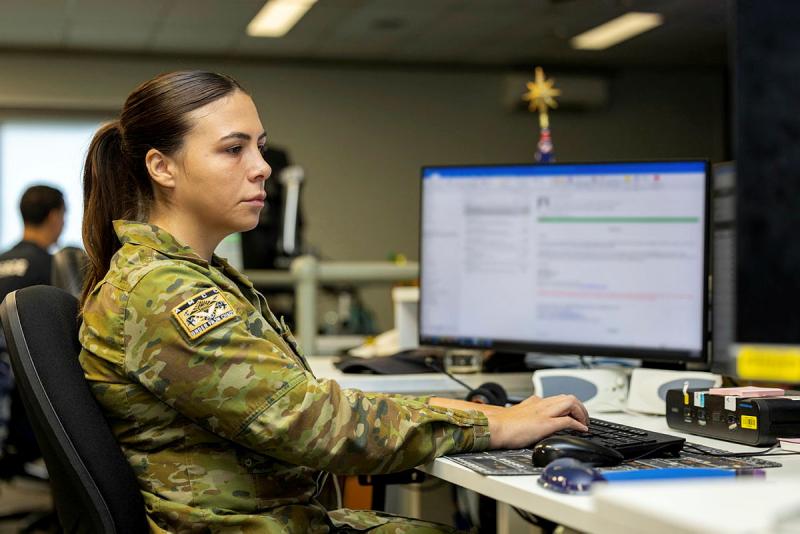 A military woman at a desk with her monitor blurred.