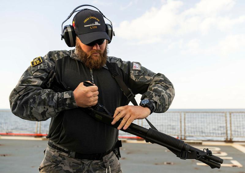 A sailor loads a shotgun
