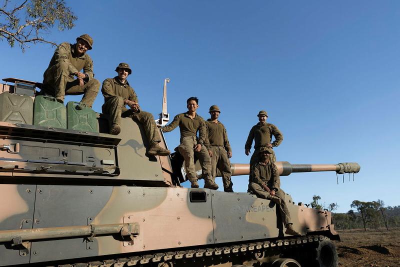 A group of Australian Army soldiers stand on top of a tank.