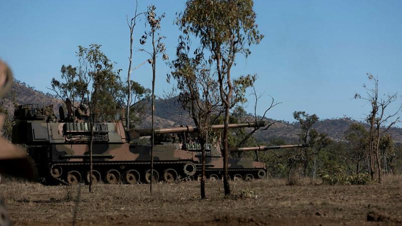 Two Australian Army tanks drive through the bush as part of a live training exercise.