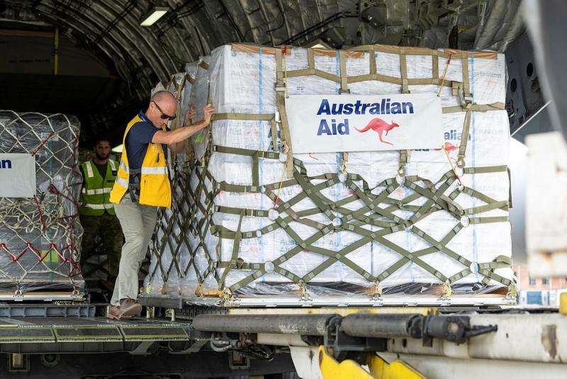 Man pushes pallet of supplies from the back of a plane