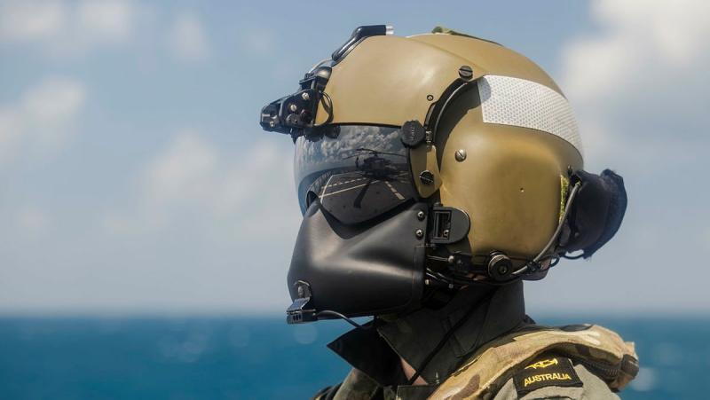 A sailor stands on a ship in aircrew gear.