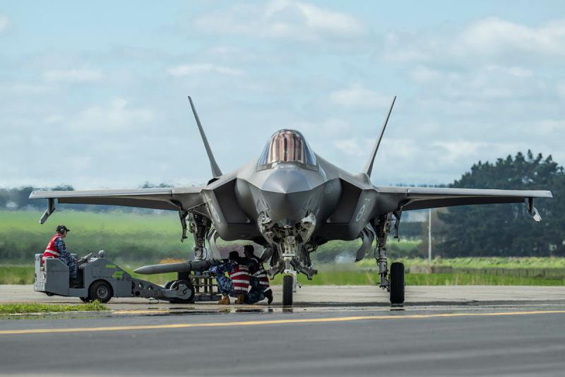Several military members work on an aircraft on the tarmac.