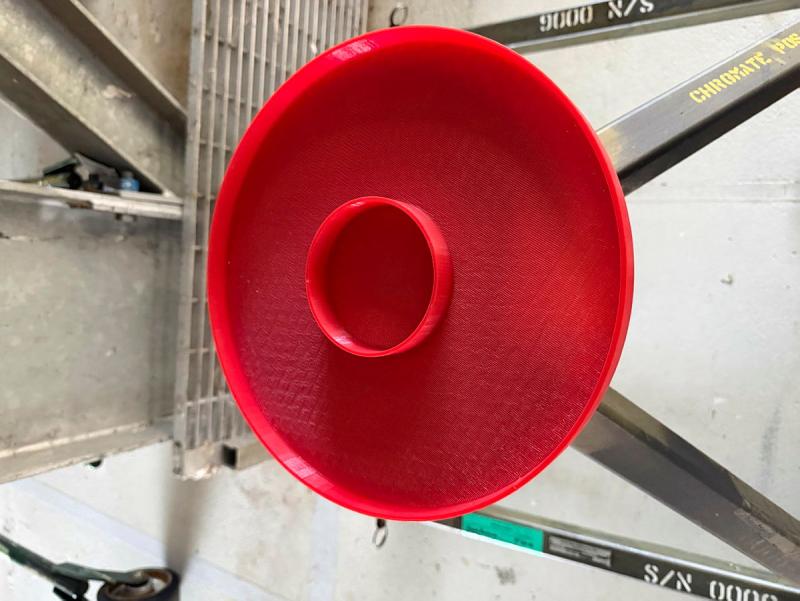 A round, red plate looking object with a smaller attached bowl in the centre.