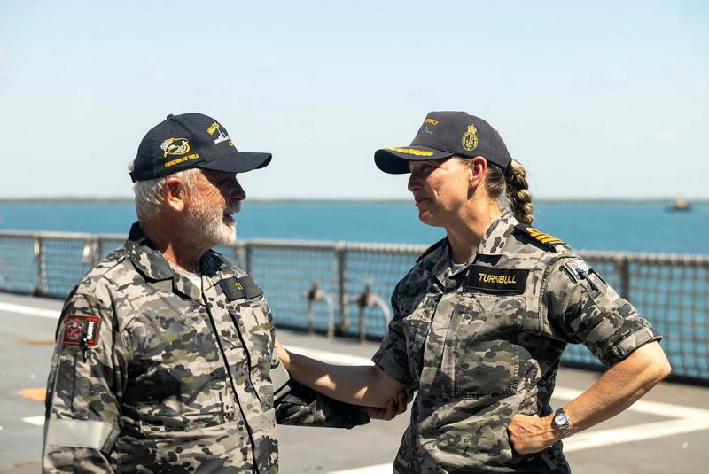 A man and a woman in Navy uniform talk and hold each other's arm.