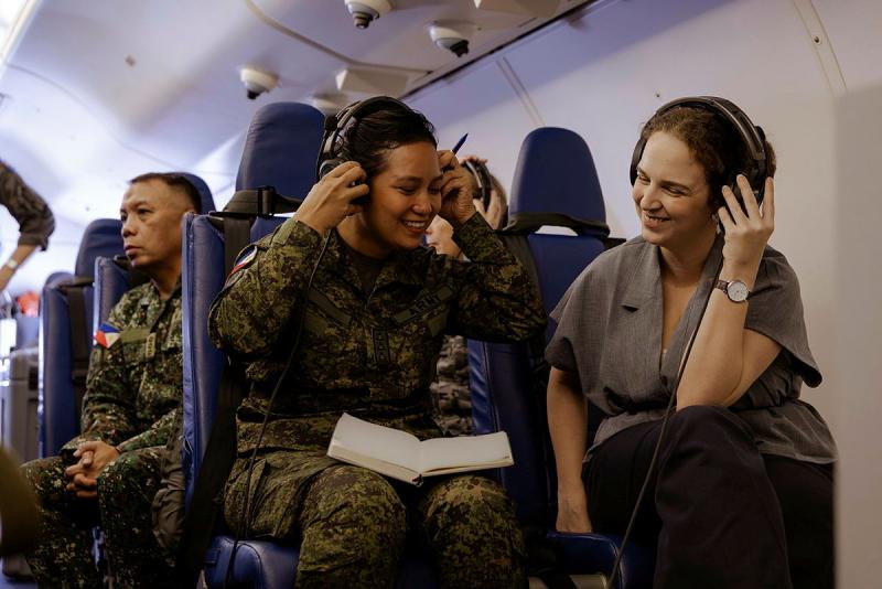 A Philippines Army officer with an Australian Embassy staff member listen to headphones and smile.