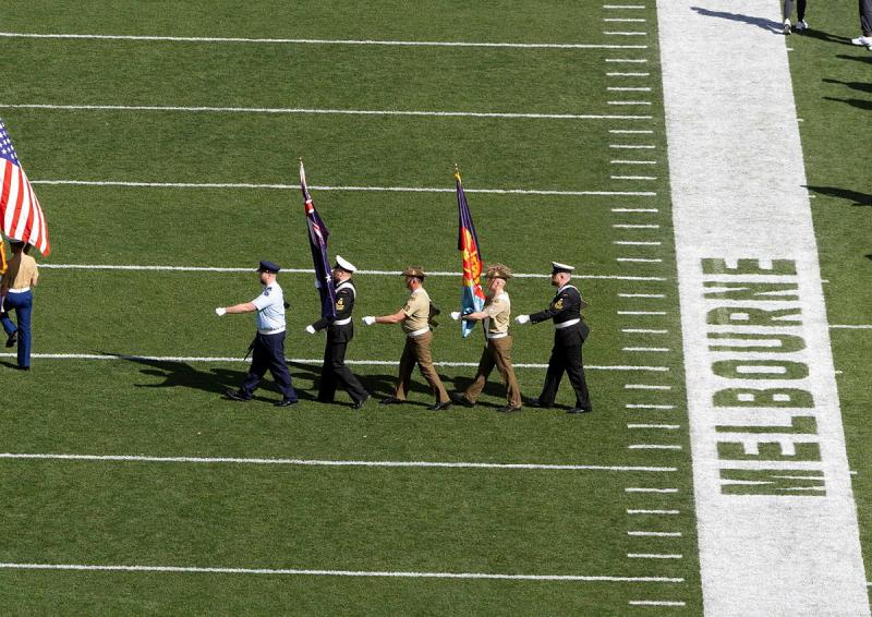 Five military members march onto a field with flags.