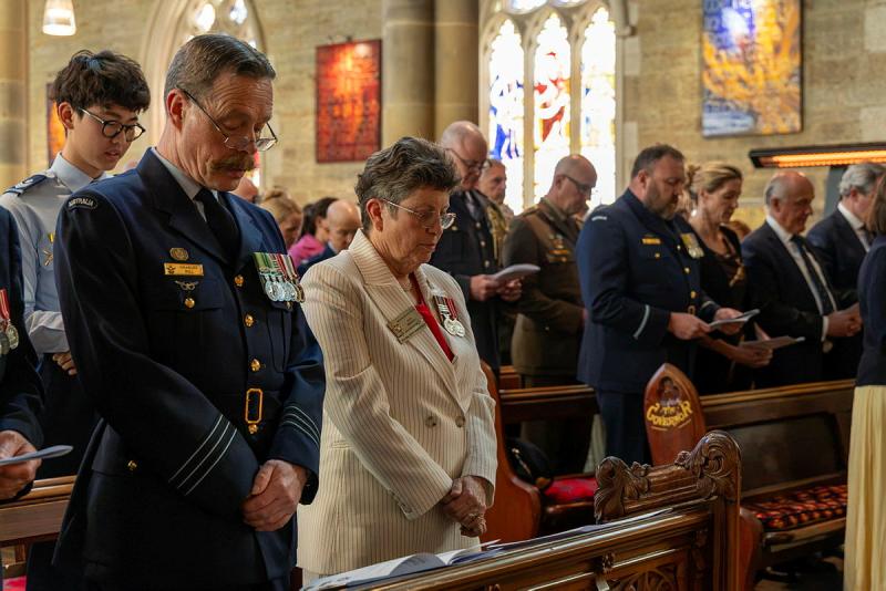 A group of military personnel stand in the pews of a church.