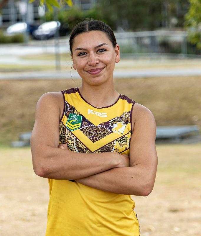 A woman in sports uniform crosses her arms over her chest.