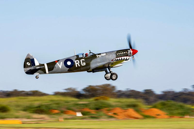 An aircraft painted with teeth, eyes and lettering takes off.